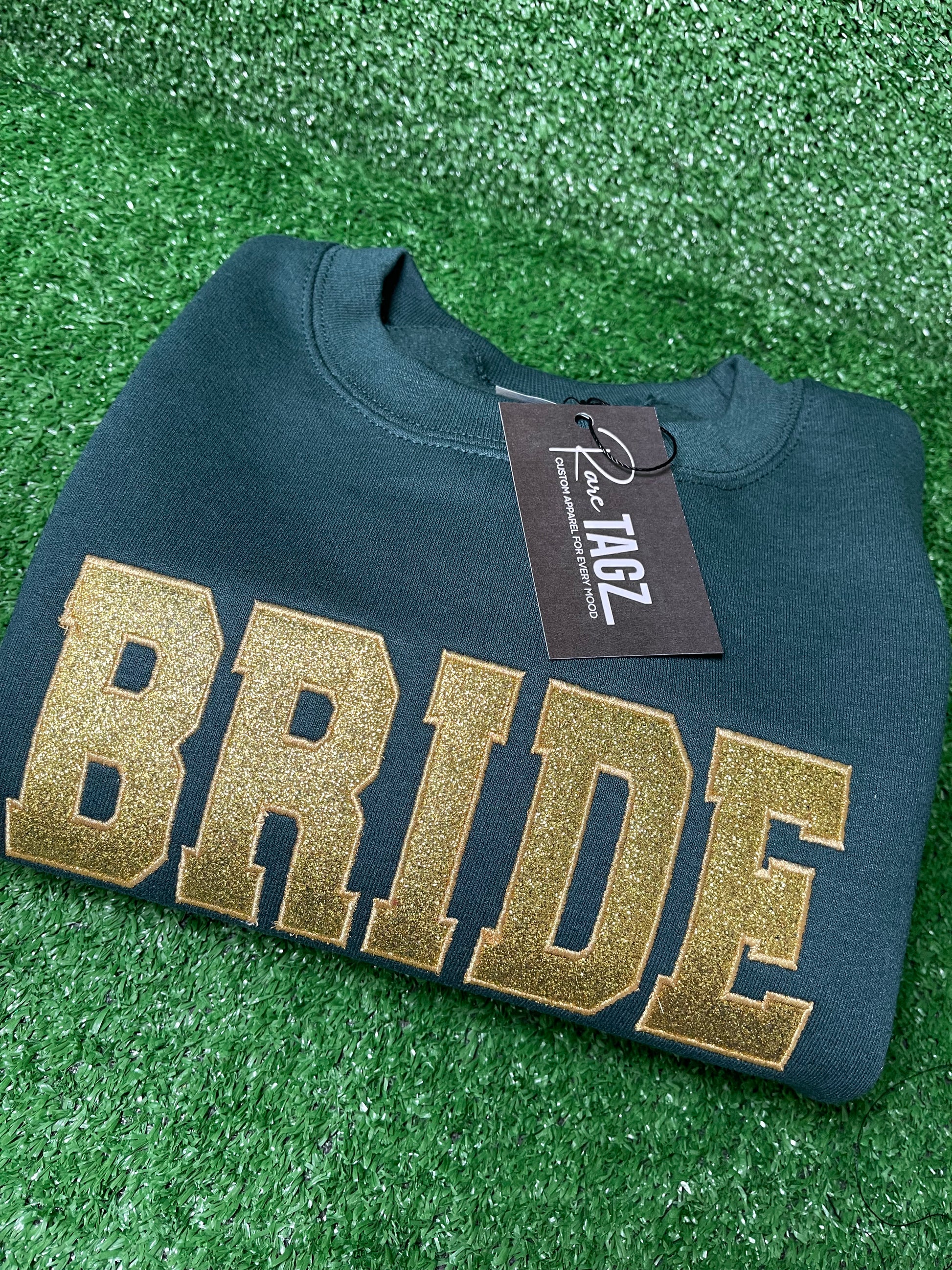 Custom BRIDE sweatshirt with gold glitter appliqué lettering featuring embroidered heart and wedding date details o the sleeves.