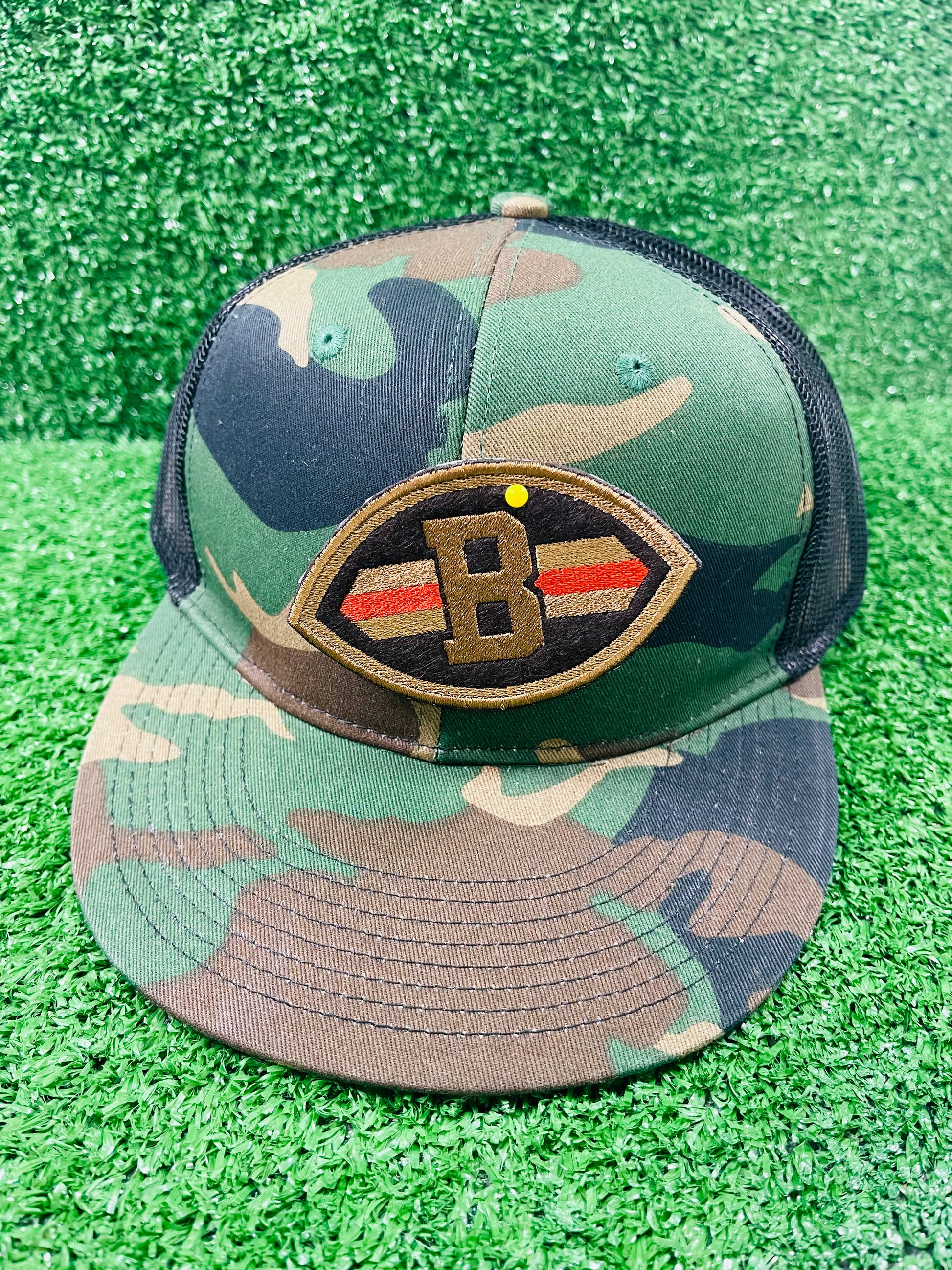 Close-up of embroidered patch shaped like a football with a Brown B in the center, dark brown background, and orange/gold stripes across each side.