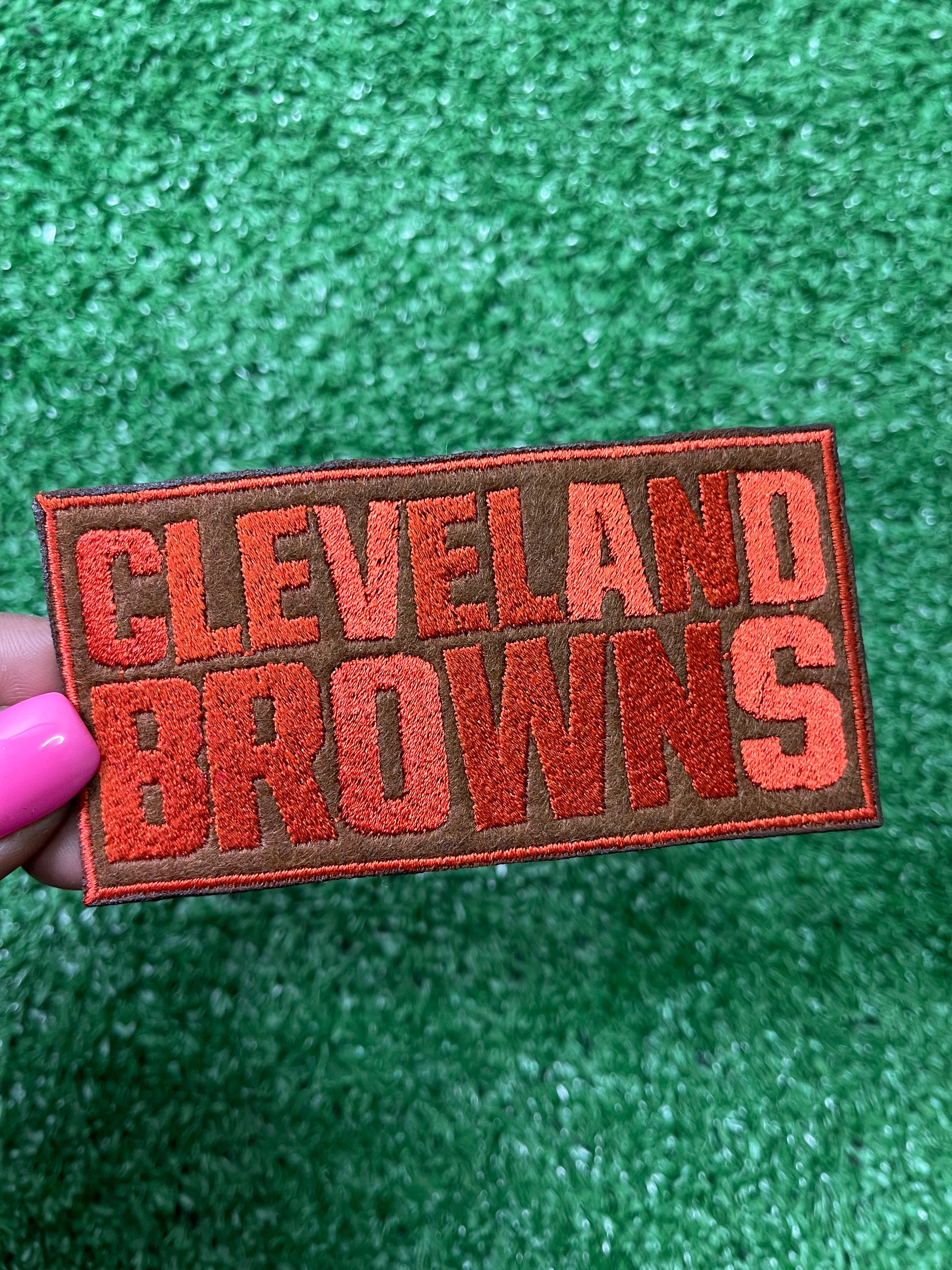 Embroidered Cleveland Browns iron-on patch in bold, orange letters on a brown background.