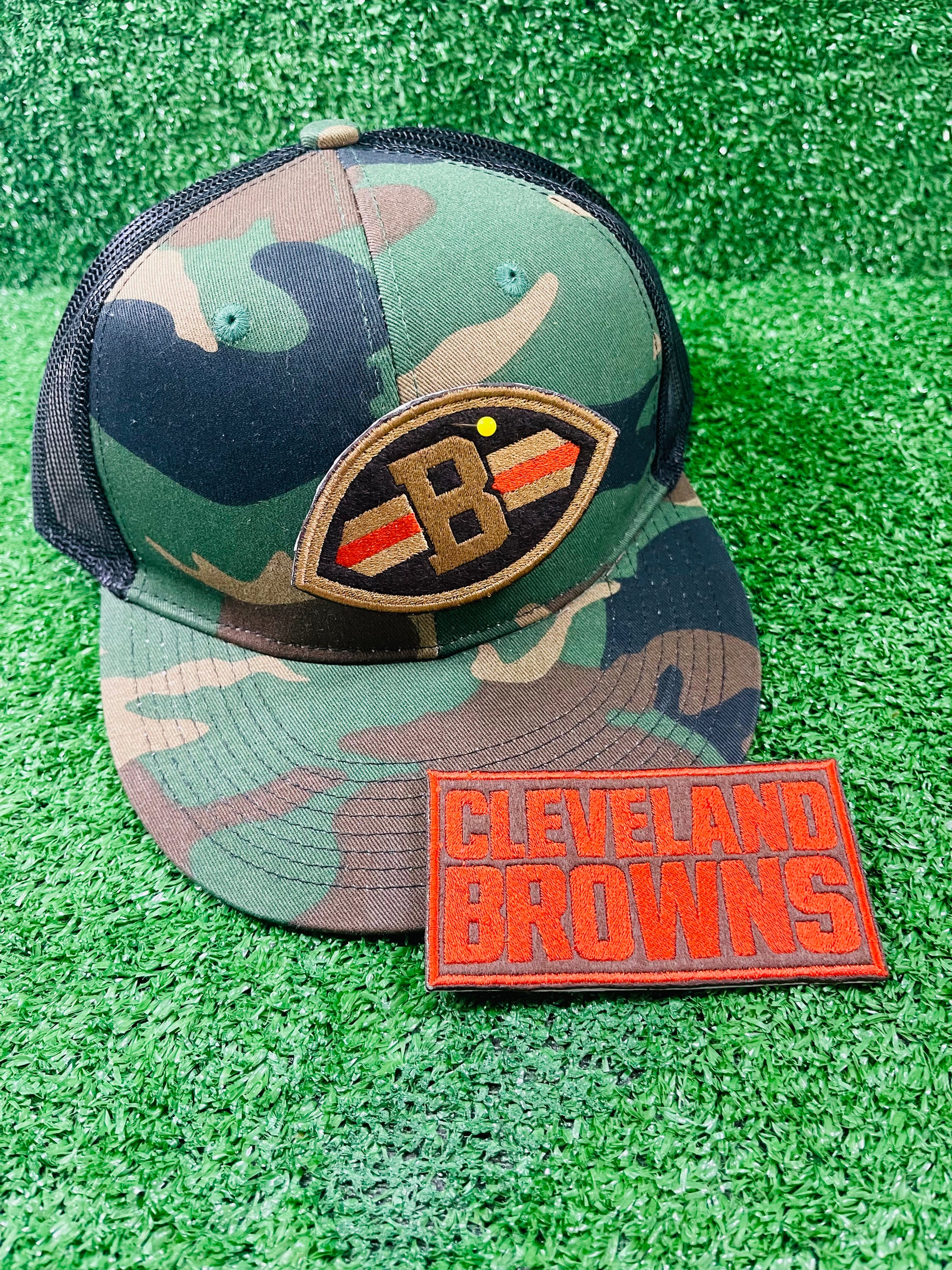 Close-up of embroidered patch shaped like a football with a Brown B in the center, dark brown background, and orange/gold stripes across each side.