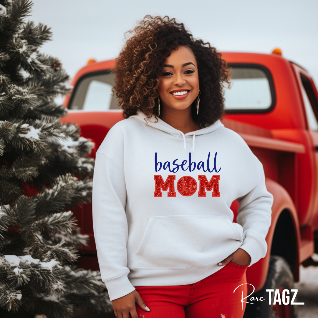 Woman wearing a custom Baseball Mom sweatshirt by Rare Tagz. A white hoodie with blue and red lettering. Featuring sporty outfits, bold embroidery perfect for proud baseball moms.