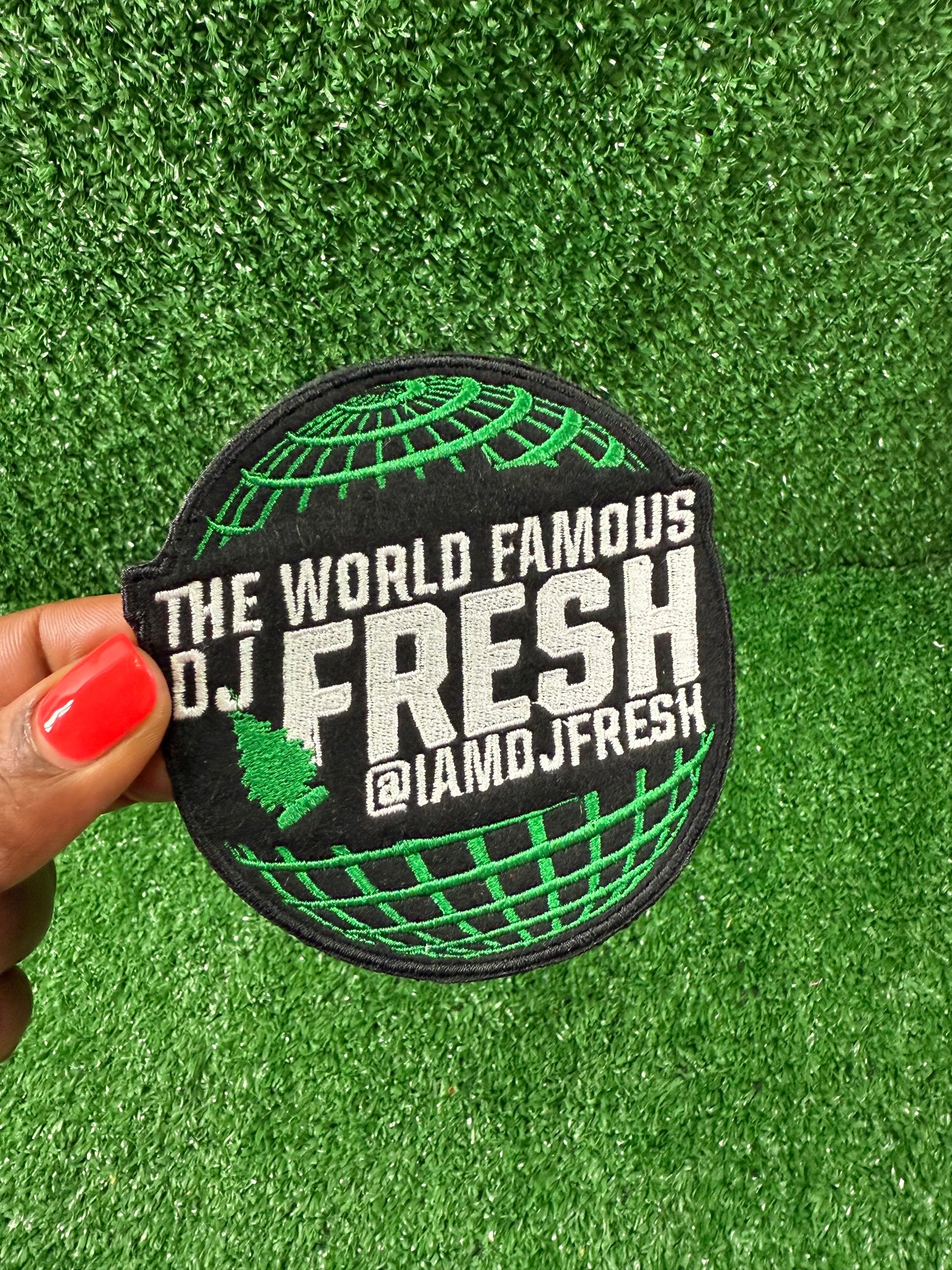 Round patch with 'The World Famous DJ Fresh' text held over a green background