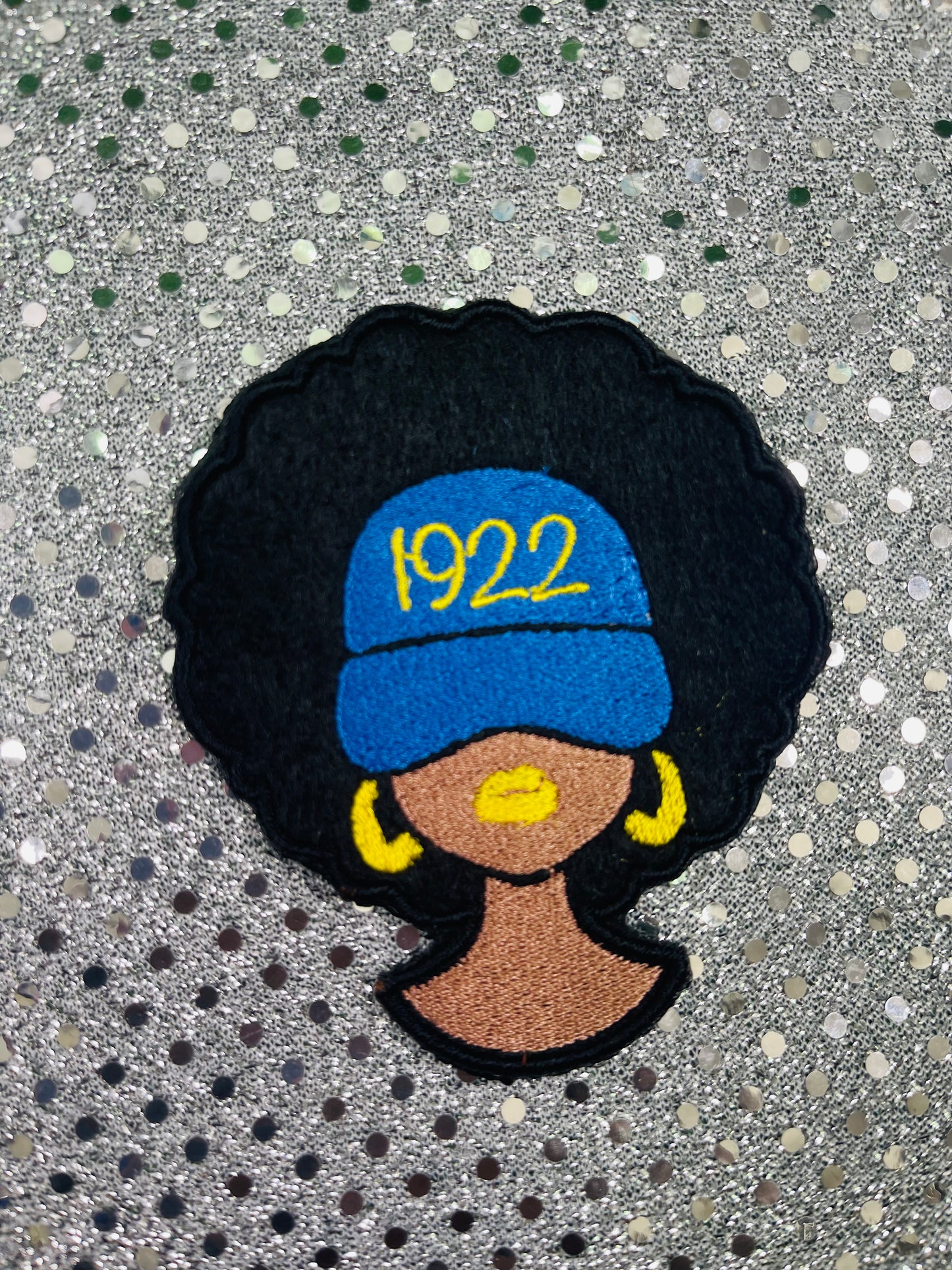 Embroidered patch of a woman wearing a blue cap with '1922' on a glittery background. Sigma Gamma Rho Patch