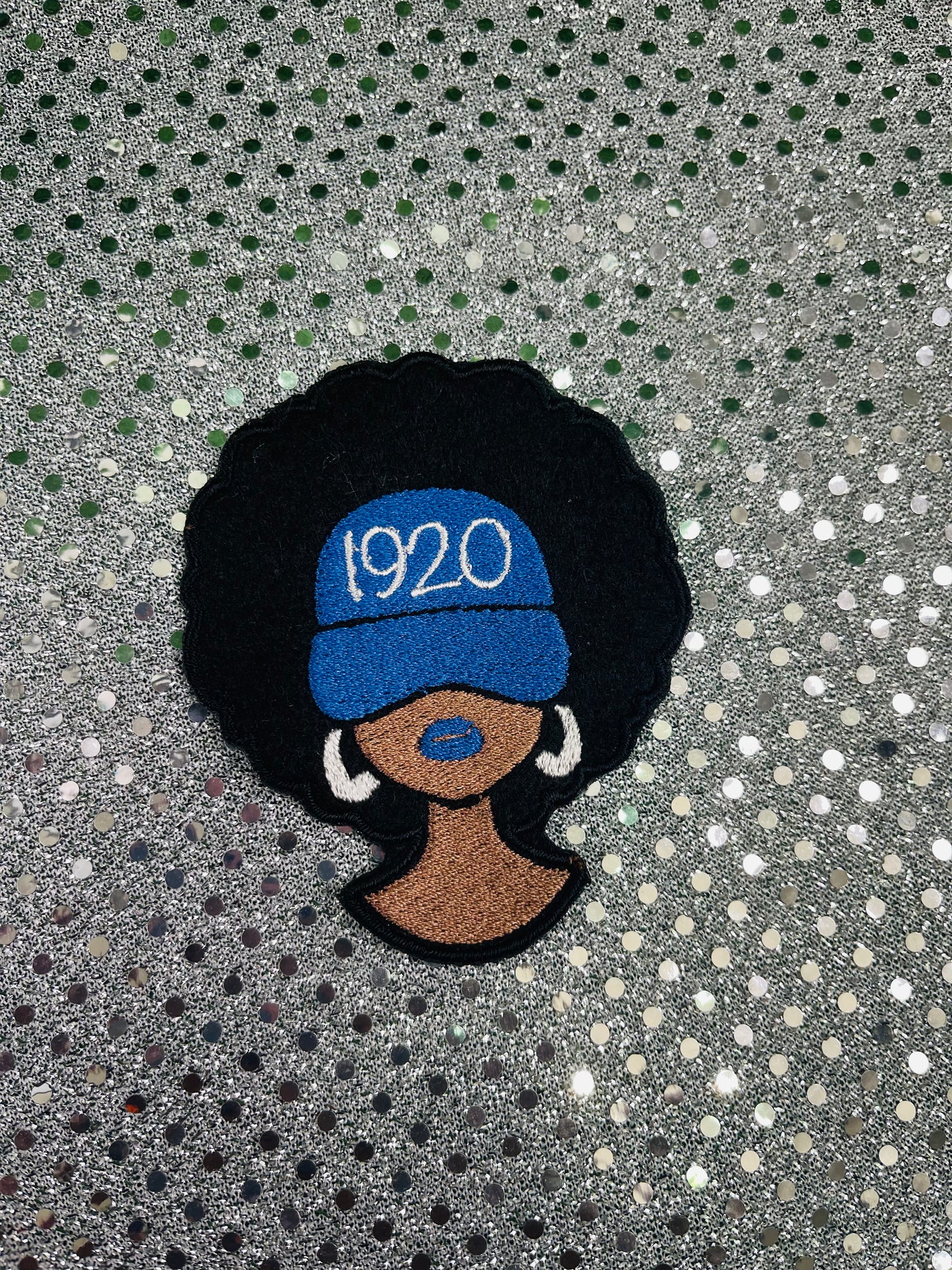 Embroidered patch of a woman with an afro wearing a blue cap with '1920' text on a glittery background. Zeta Sigma Theta