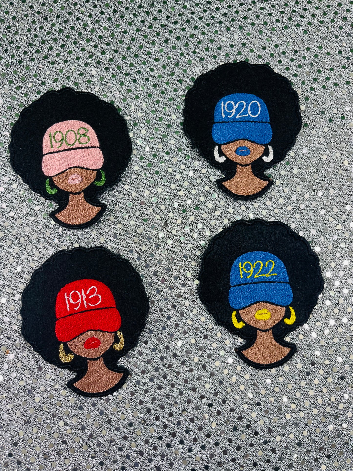 Four embroidered patches of women with different colored hats and years on a textured background. NPHC Sorority Patches.