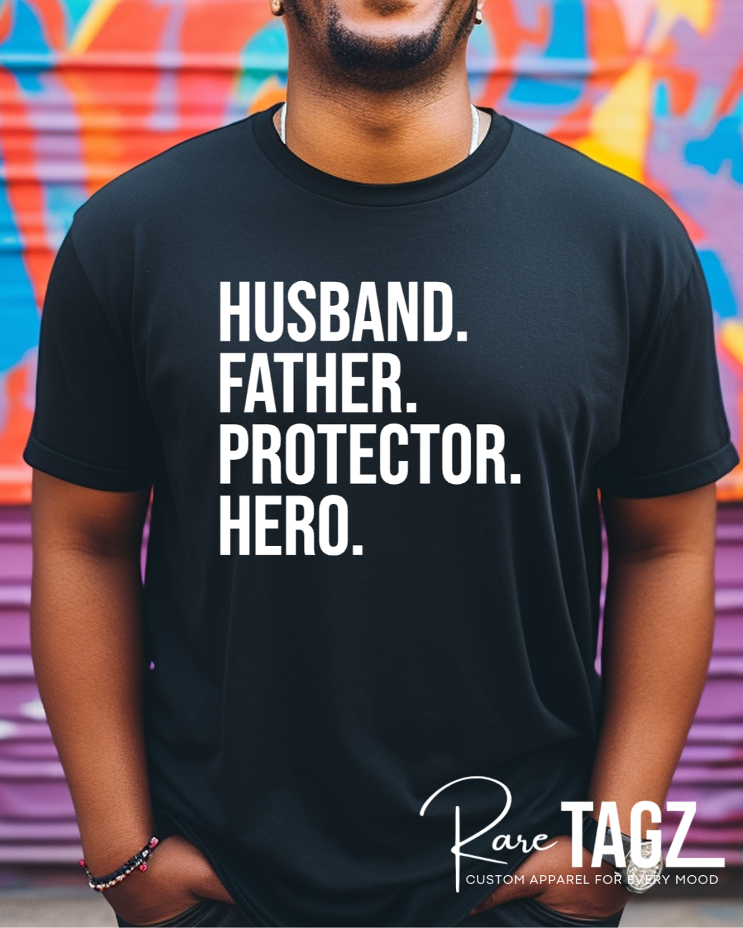 Black t-shirt with bold white text reading Husband Father Protector Hero from Rare Tagz, perfect for Father's Day.