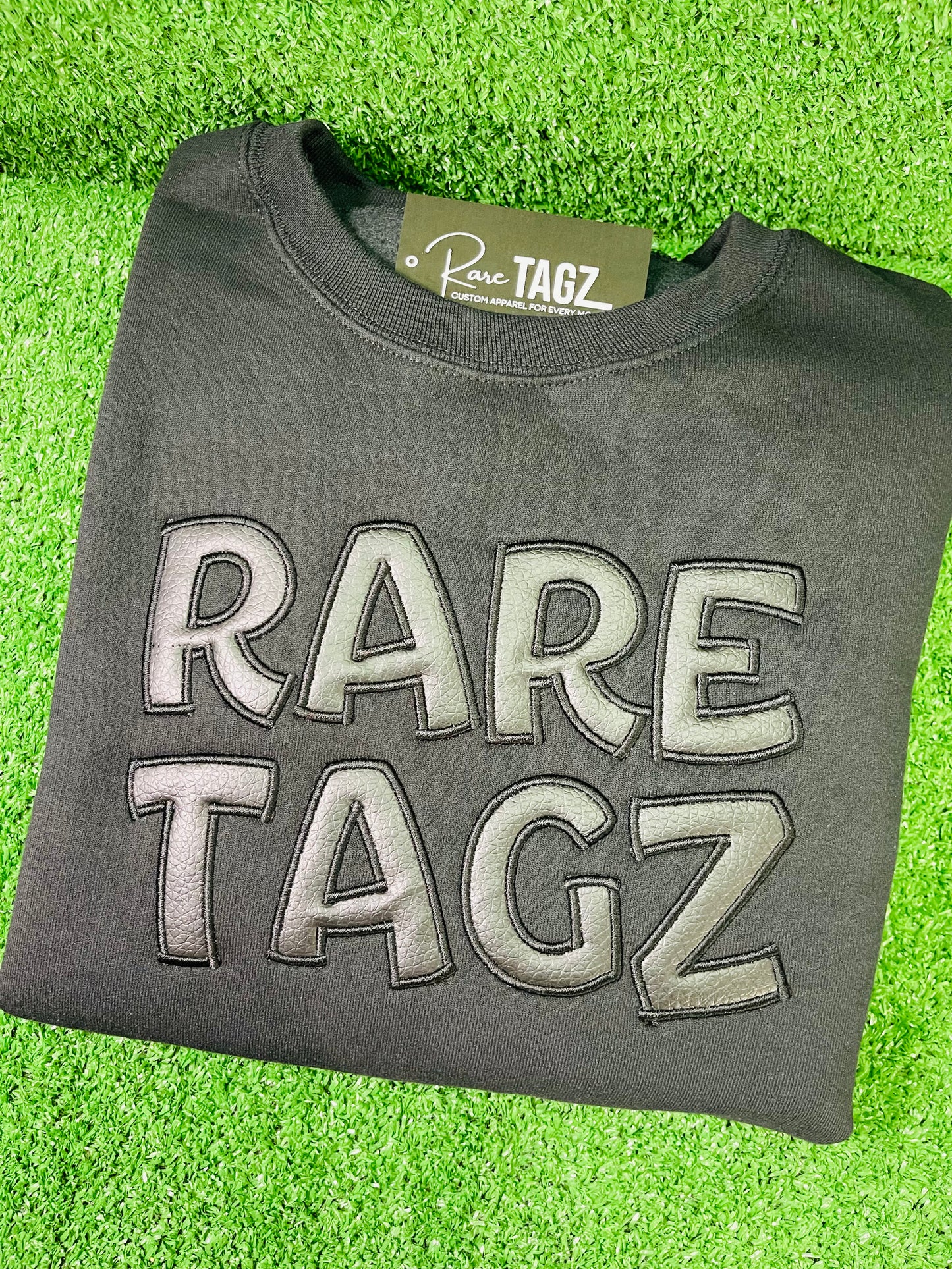 Black Sweatshirt featuring bold raised faux leather Rare Tagz lettering showcasing sleek design and premium craftsmanship.