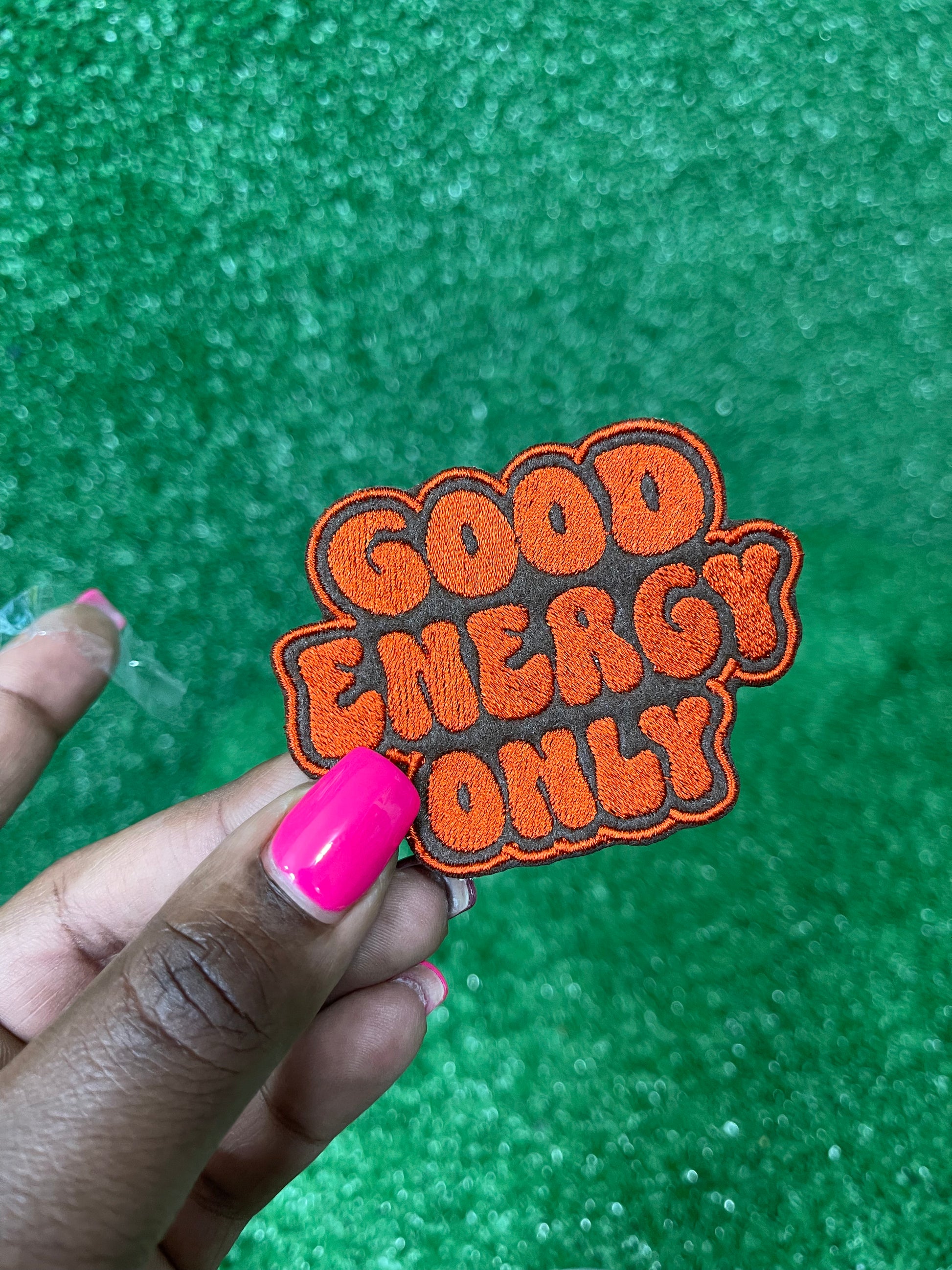 Good Energy patch with bold embroidered letters on a brown background.