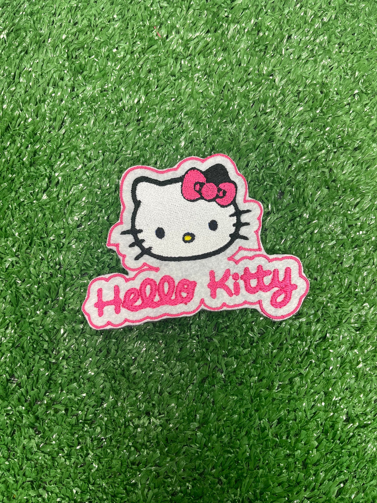 A close up of a Hello Kitty patch featuring the character's signature bow and face, ideal for adding a cute and playful touch to clothing or accessories.