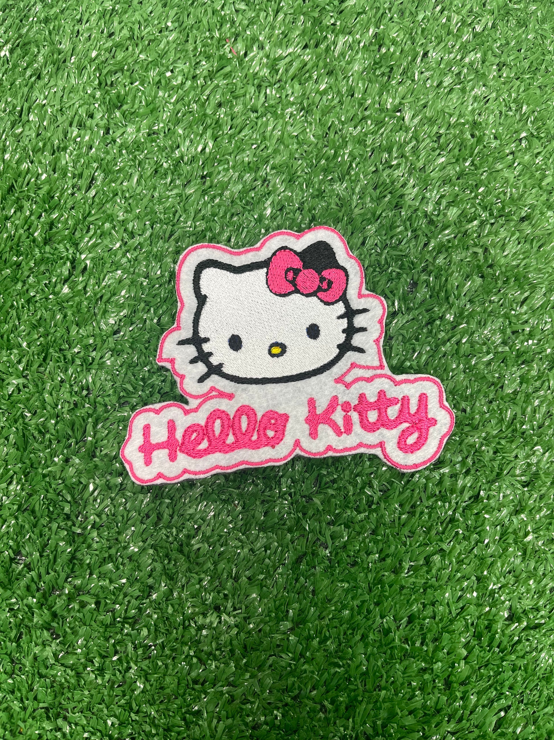 A close up of a Hello Kitty patch featuring the character's signature bow and face, ideal for adding a cute and playful touch to clothing or accessories.