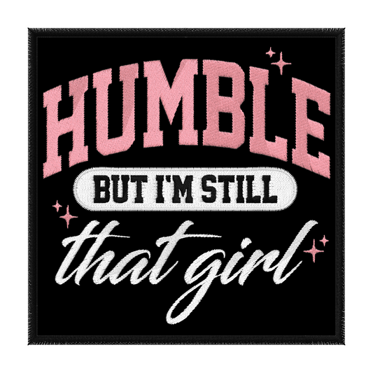 Square black patch with bold pink text at the top that says Humble white text underneath that reads but I'm still and cursive white text at the bottom says that girl. Small Pink Sparkle accent the design. Iron on Patch embroidered.