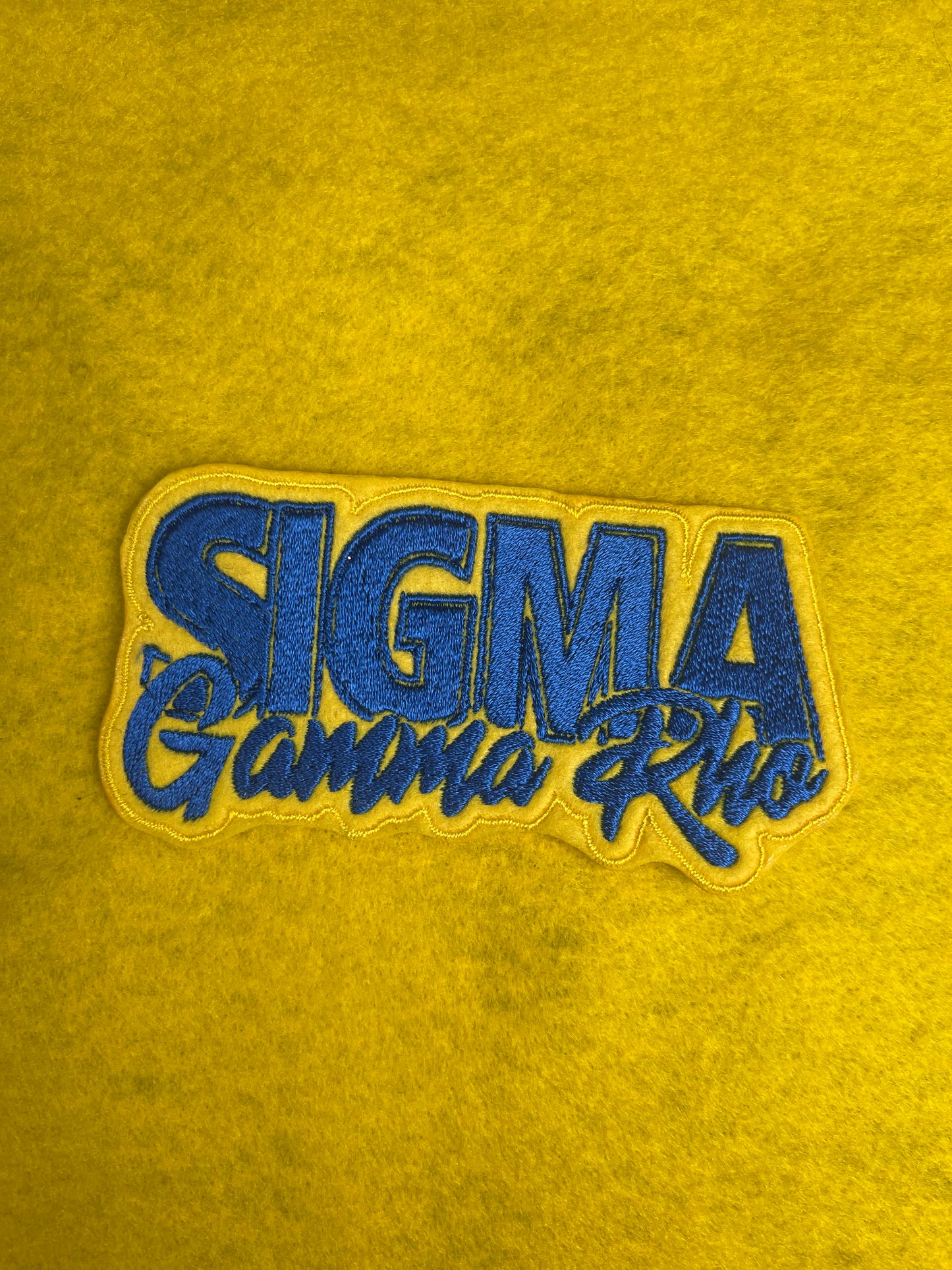 A patch featuring Sigma Gamma Rho with vibrant yellow filling the background and royal blue words.