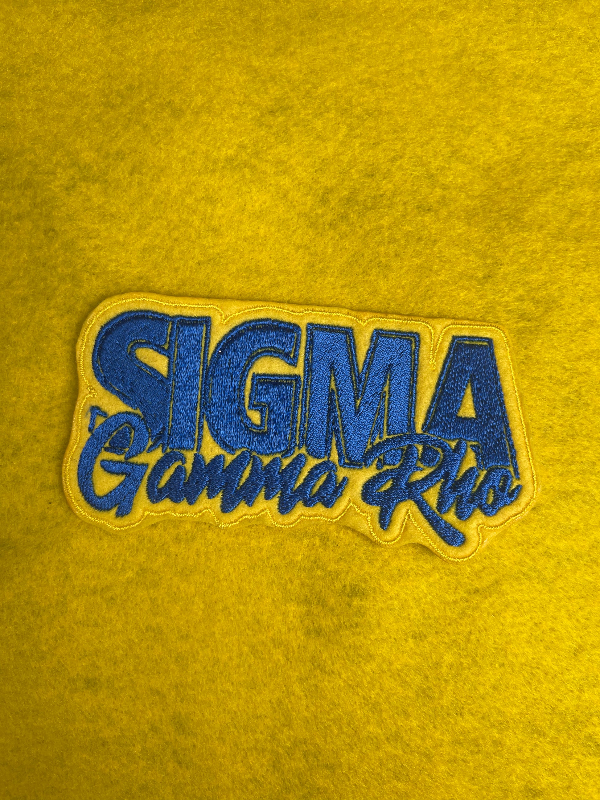 A patch featuring Sigma Gamma Rho with vibrant yellow filling the background and royal blue words.