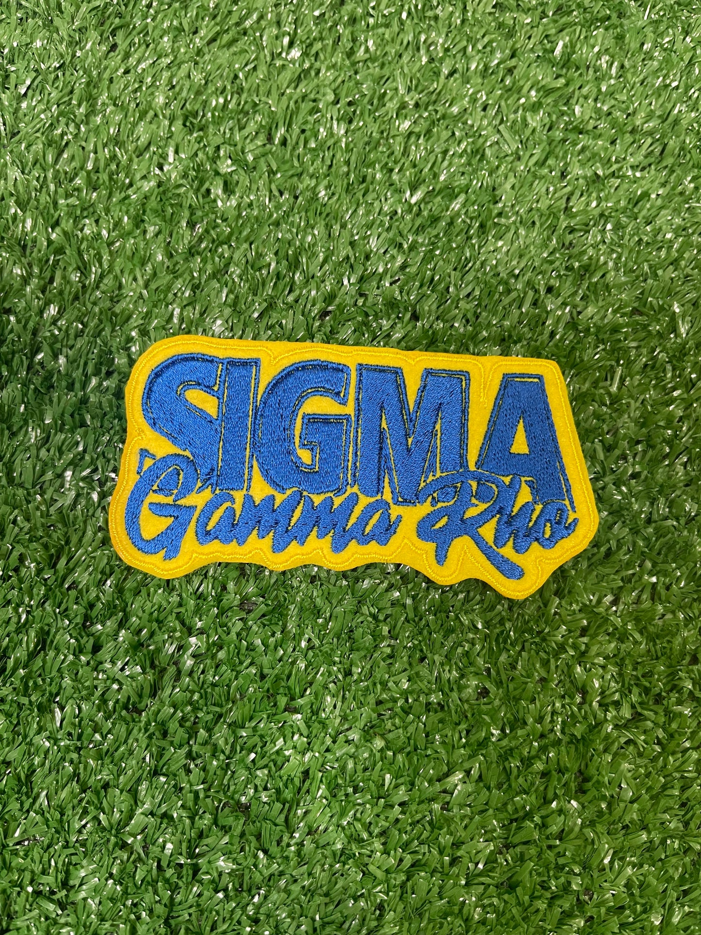A patch featuring Sigma Gamma Rho with vibrant yellow filling the background and royal blue words.