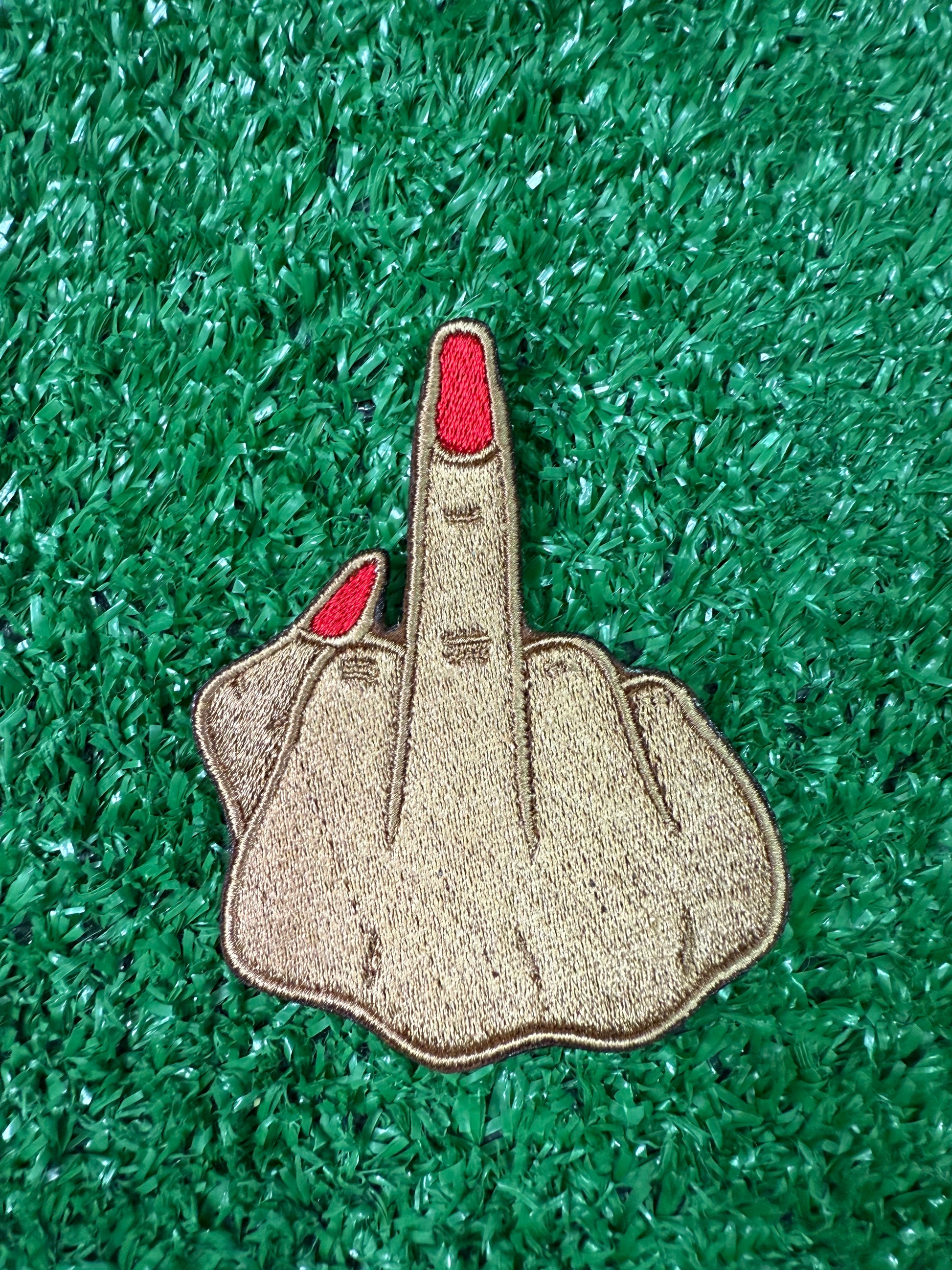 Patch of a hand with a red finger on green artificial grass