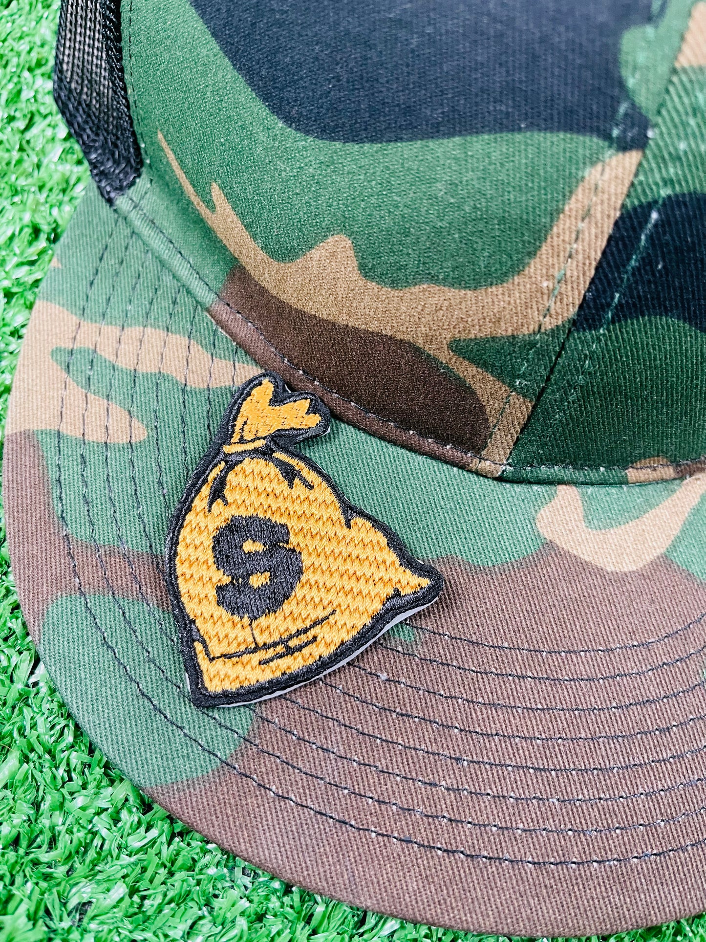 Embroidered patch depicting a money bag with a dollar sign, featuring black and gold colors for a bold and eye-catching design.