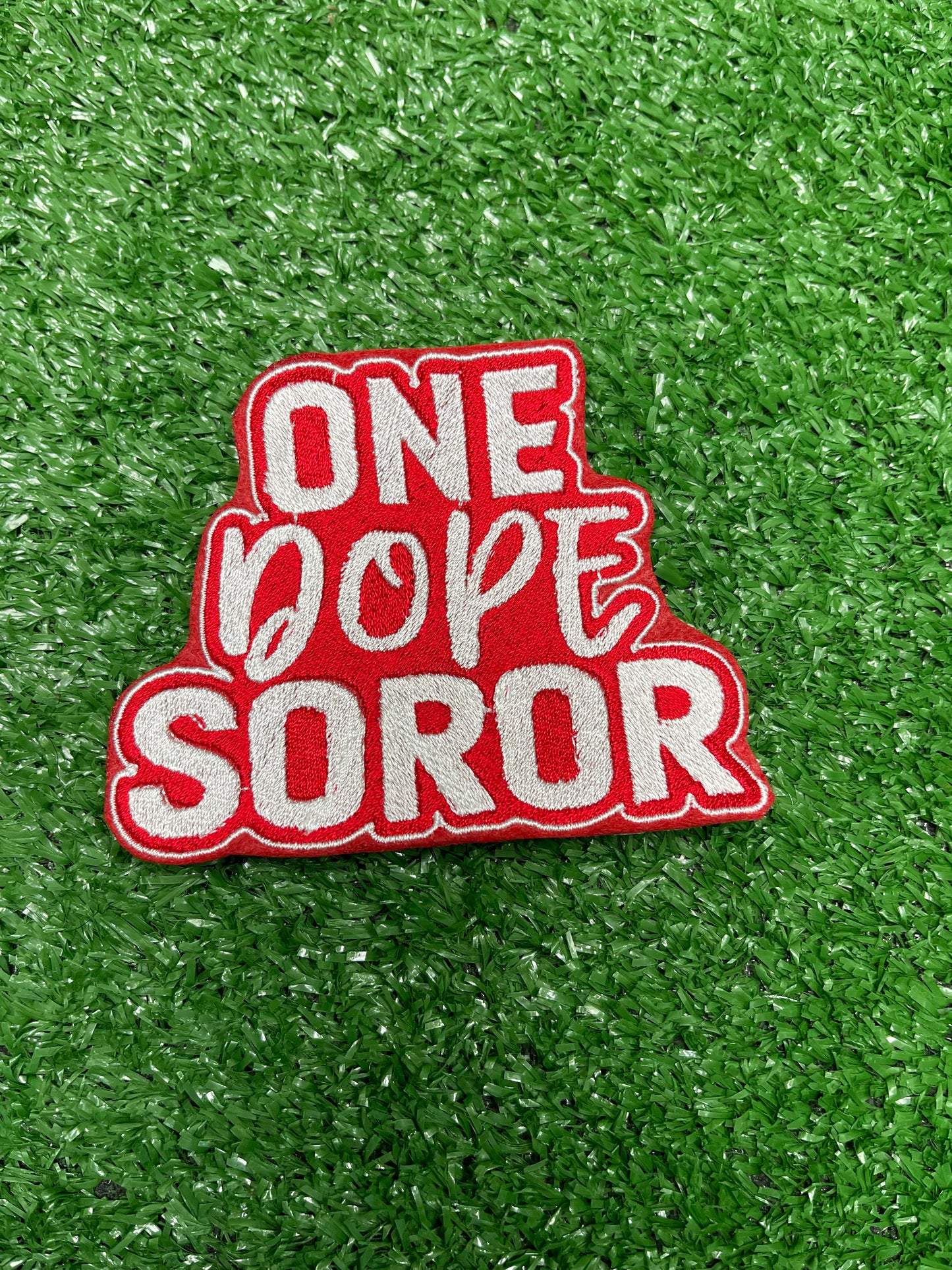 Embroidered patch with bold red and white lettering that says One Dope Soror on a green grass background.