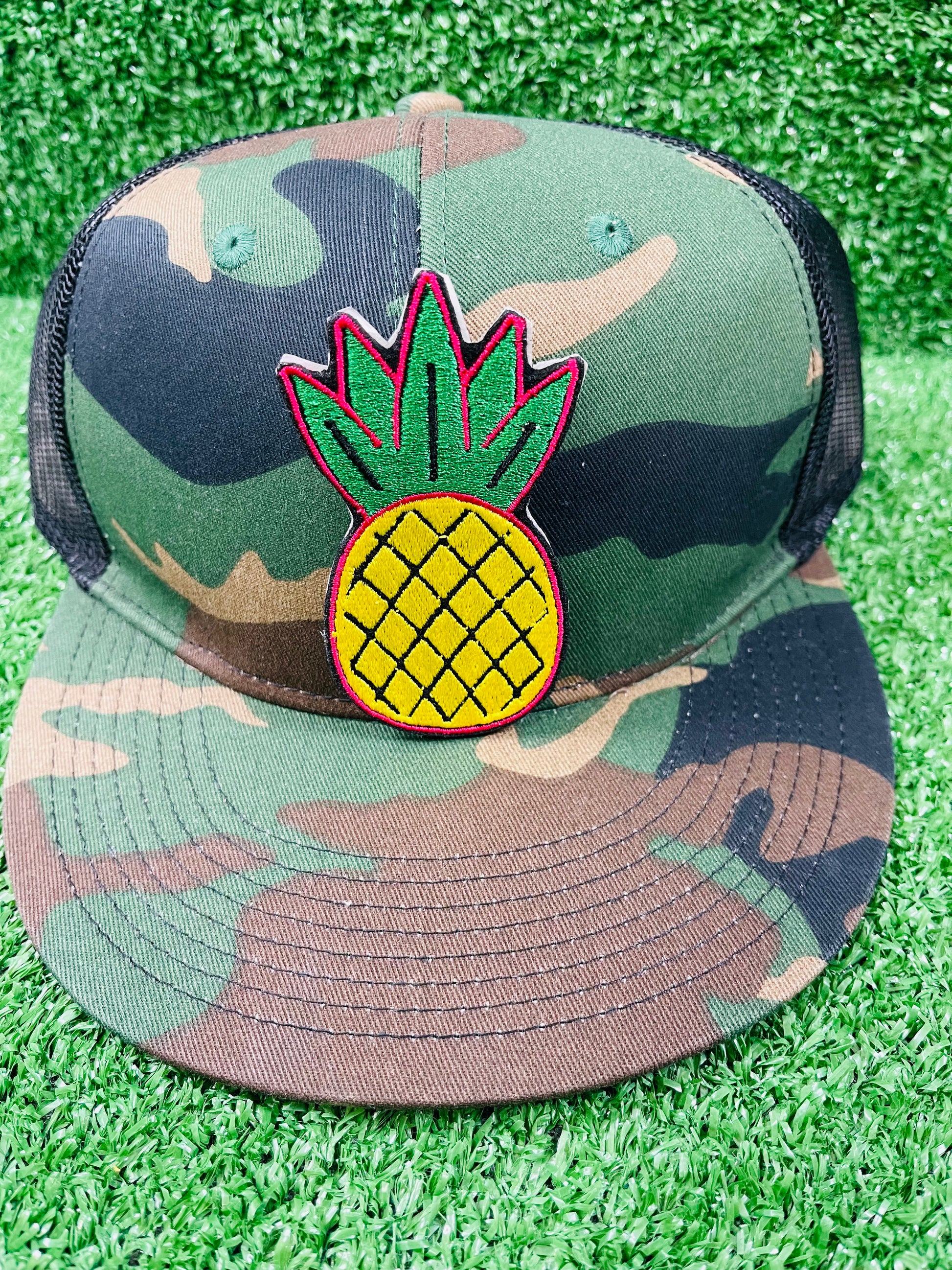 Camouflage cap with pineapple patch on a grassy background