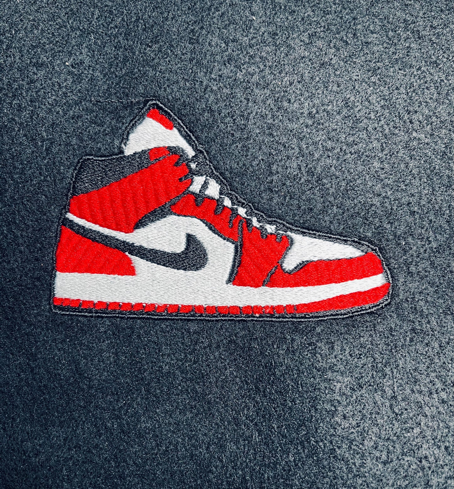 Embroidered iron on patch of a red and white nike style air Jordan sneaker with black accents designed by Rare Tagz.
Perfect for streetwear, sneakerheads, and DIY jackets or bag designs.