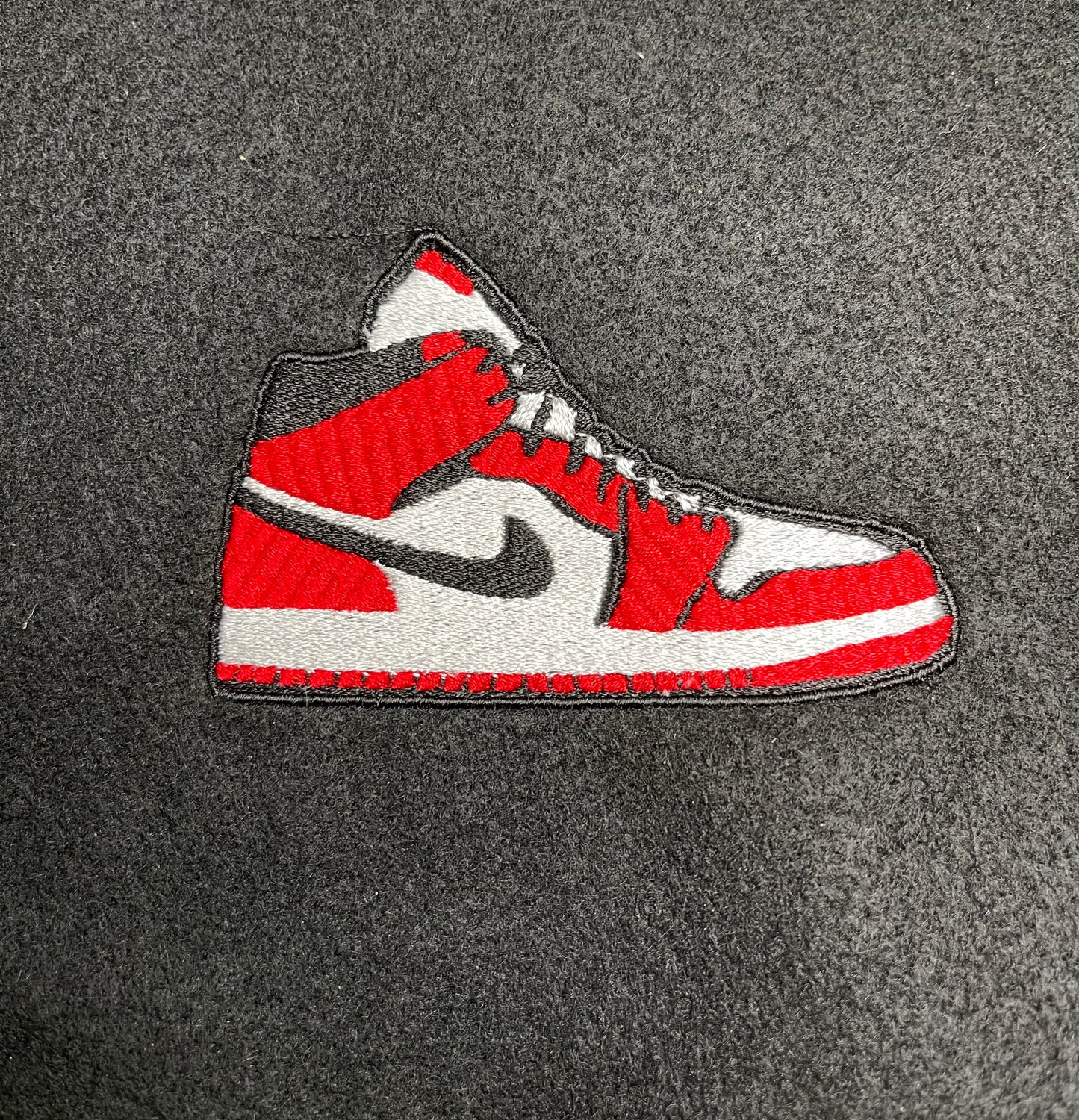 Embroidered iron on patch of a red and white nike style air Jordan sneaker with black accents designed by Rare Tagz.
Perfect for streetwear, sneakerheads, and DIY jackets or bag designs.