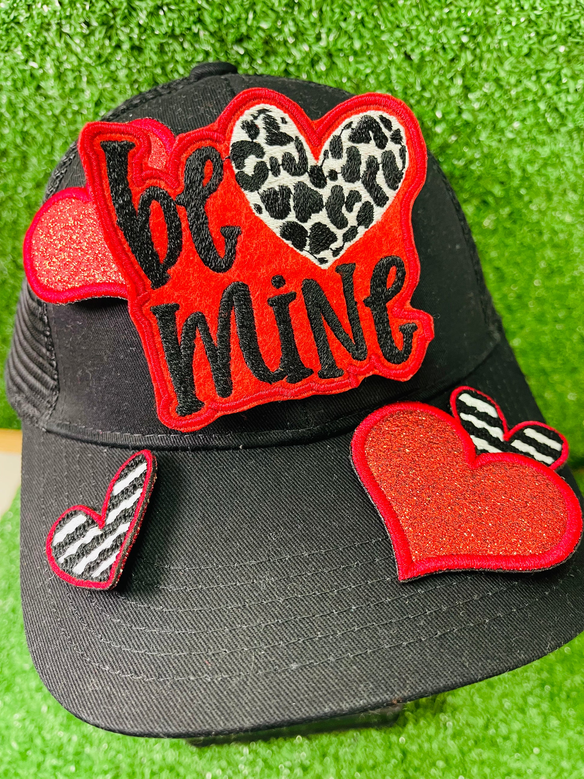 Valentine's Day patch set featuring a bold Be Mine design with a leopard heart, two red glitter hearts, and two black and white zebra stripped hearts displayed on a green grass background.