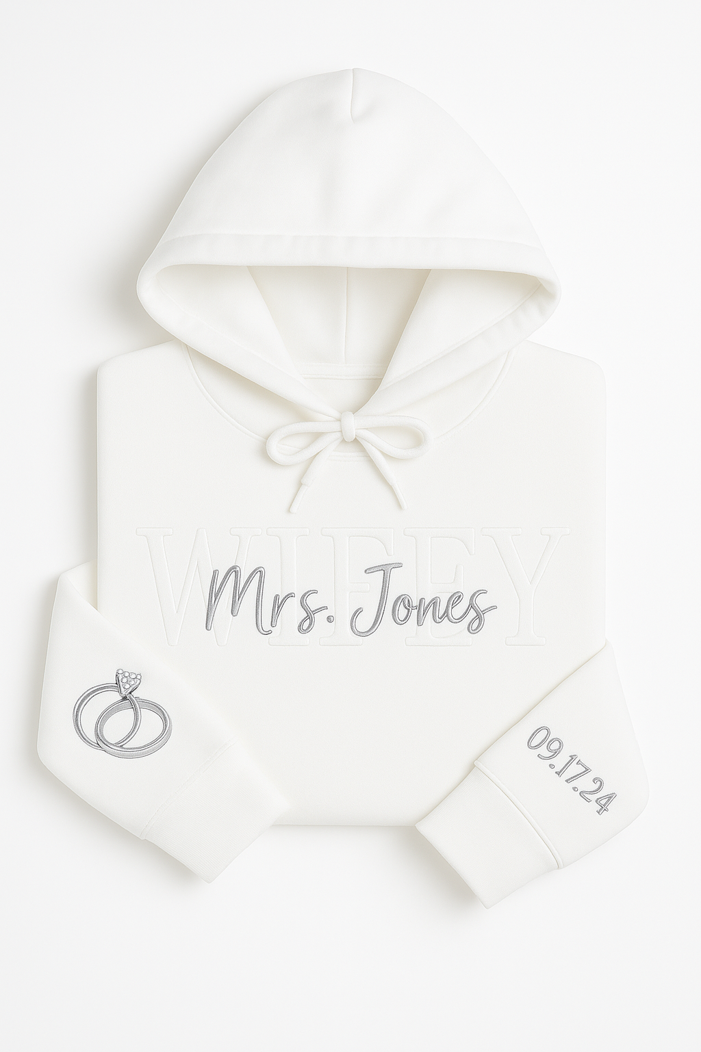 White custom embroidered hoodie with WIFEY and Mrs. Foster stitched on the front, wedding rings embroidered on one sleeve and wedding date on the other, displayed on a white background.