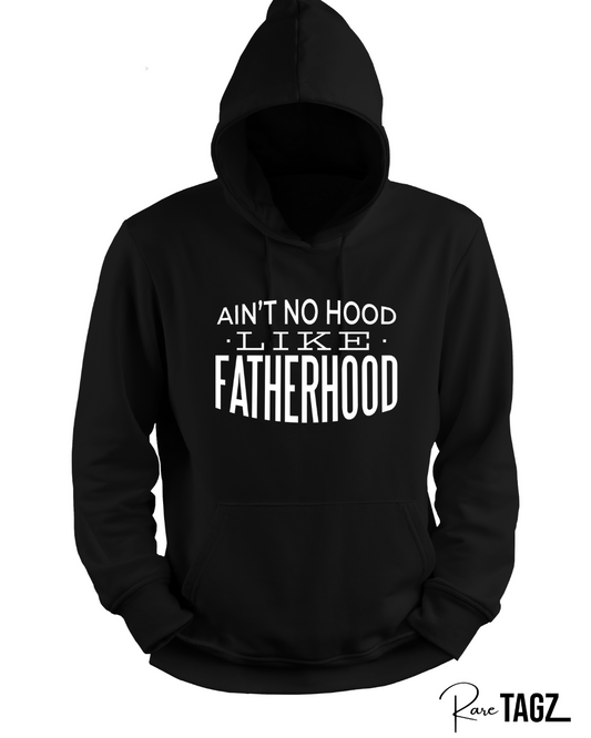 Custom hoodie with the phrase 'Ain't No Hood Like Fatherhood' printed on the front. The design features bold, eye-catching typography, celebrating the unique and rewarding experience of fatherhood. Perfect for dads who want to express their pride and love for their role.