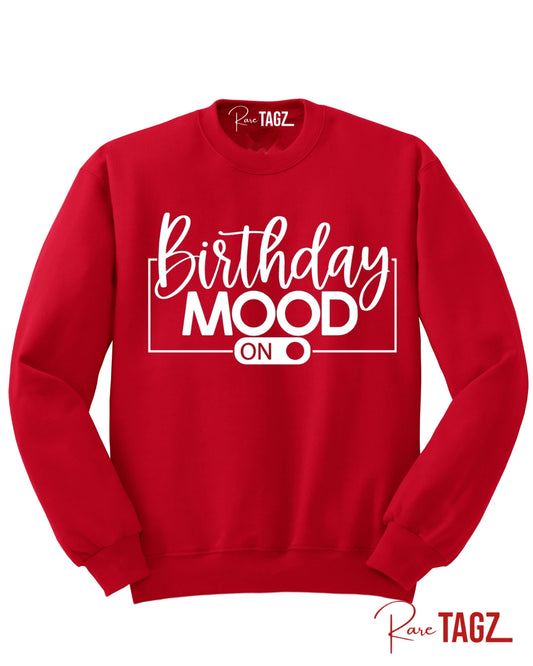 Bold red crewneck sweatshirt featuring the phrase Birthday Mood On in stylish white lettering with an on-switch graphic. This cozy and festive birthday sweatshirt by Rare Tagz is perfect for birthday celebrations, photo ops, and turning up your birthday energy in style.