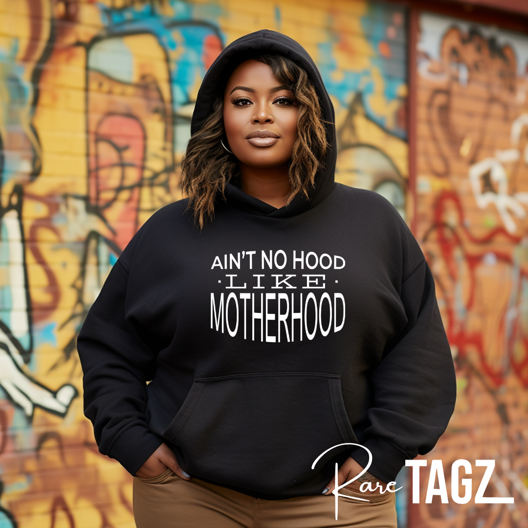 Custom hoodie with the phrase 'Ain't No Hood Like Motherhood' printed on the front. The design features bold, eye-catching typography, celebrating the unique and rewarding experience of motherhood. Perfect for moms who want to express their pride and love for their role in a stylish and comfortable way.