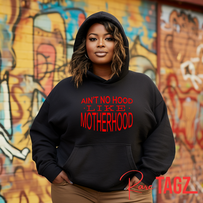 Custom hoodie with the phrase 'Ain't No Hood Like Motherhood' printed on the front. The design features bold, eye-catching typography, celebrating the unique and rewarding experience of motherhood. Perfect for moms who want to express their pride and love for their role in a stylish and comfortable way.