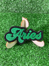 Embroidered iron-on patch with the word Aries in a bold decorative font.