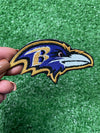 Detailed view of a Baltimore Ravens patch showcasing the team's raven head logo with striking colors, perfect for customizing jackets, trucker hats, or bags with team pride.