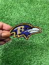 Detailed view of a Baltimore Ravens patch showcasing the team's raven head logo with striking colors, perfect for customizing jackets, trucker hats, or bags with team pride.