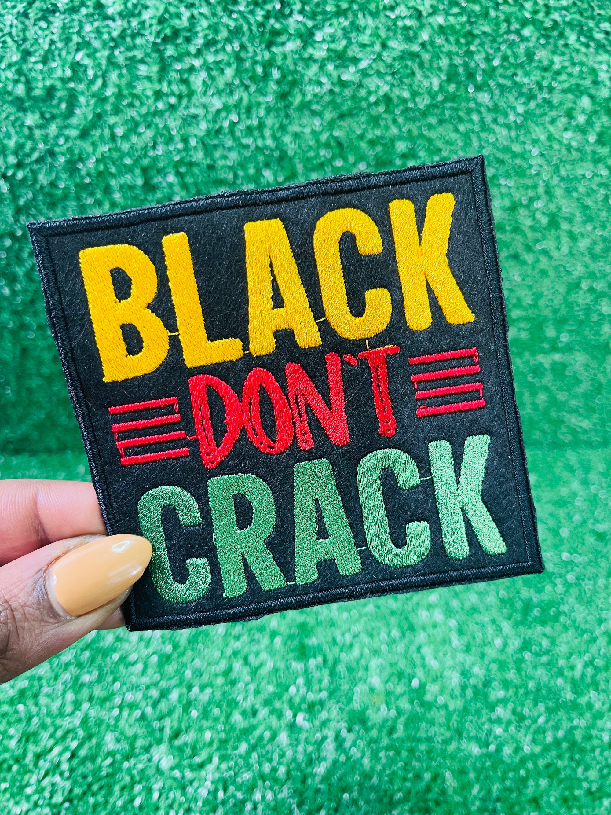 Embroidered patch with the bold text reading Black Don't Crack in yellow, red, and green on a black background.