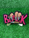 Embroidered iron-on patch featuring the word Black held by a hand with stylish-black and white nails. The letters Black are embroidered in bold pink stitching.