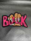 Embroidered iron-on patch featuring the word Black held by a hand with stylish-black and white nails. The letters Black are embroidered in bold pink stitching.