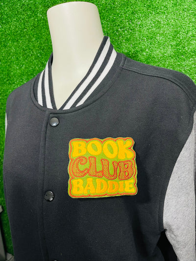 Bold and trendy iron-on patch featuring the phrase 'Book Club Baddie' in stylish lettering. Perfect for book lovers, this high-quality embroidered patch showcases vibrant colors and intricate stitching, ideal for adding a literary flair to jackets, backpacks, hats, and other clothing items.