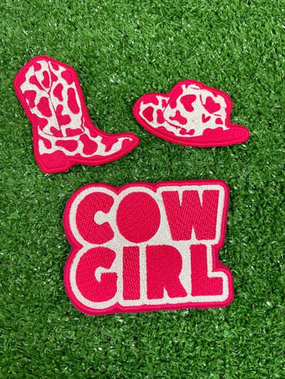 Set of three cow-girl themed iron-on patches: a detailed pink and white cowboy hat, a pink cowboy boot, and a patch with the words COWGIRL in bold pink letters on a white background.