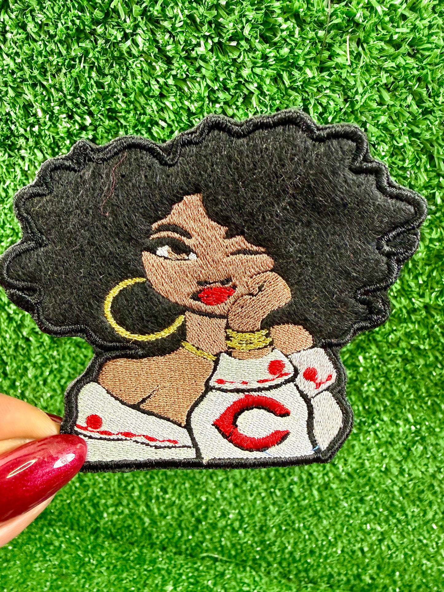 Embroidered patch of a woman with a Cincinnati Reds logo on her shirt. Game Day opening day patch