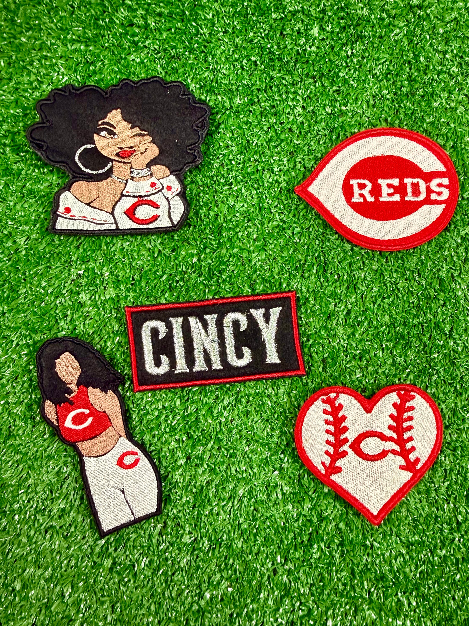 Collection of Cincinnati Reds-themed patches on a green background