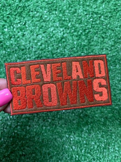 Embroidered Cleveland Browns iron-on patch in bold, orange letters on a brown background.