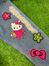 A set of four embroidered patches displayed on bright green grass. The set includes a white kitty wearing a pink hoodie, and holding an iced coffee, a pink bow, a green flower with a yellow center, and a pink flower with a yellow center. The patches are digitized and embroidered with high-quality stitching.