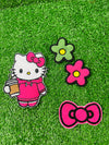 A set of four embroidered patches displayed on bright green grass. The set includes a white kitty wearing a pink hoodie, and holding an iced coffee, a pink bow, a green flower with a yellow center, and a pink flower with a yellow center. The patches are digitized and embroidered with high-quality stitching.