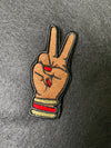 Custom embroidered Deuces patch depicting a hand with two fingers raised in a peace sign adorned with bangles and matching nails.