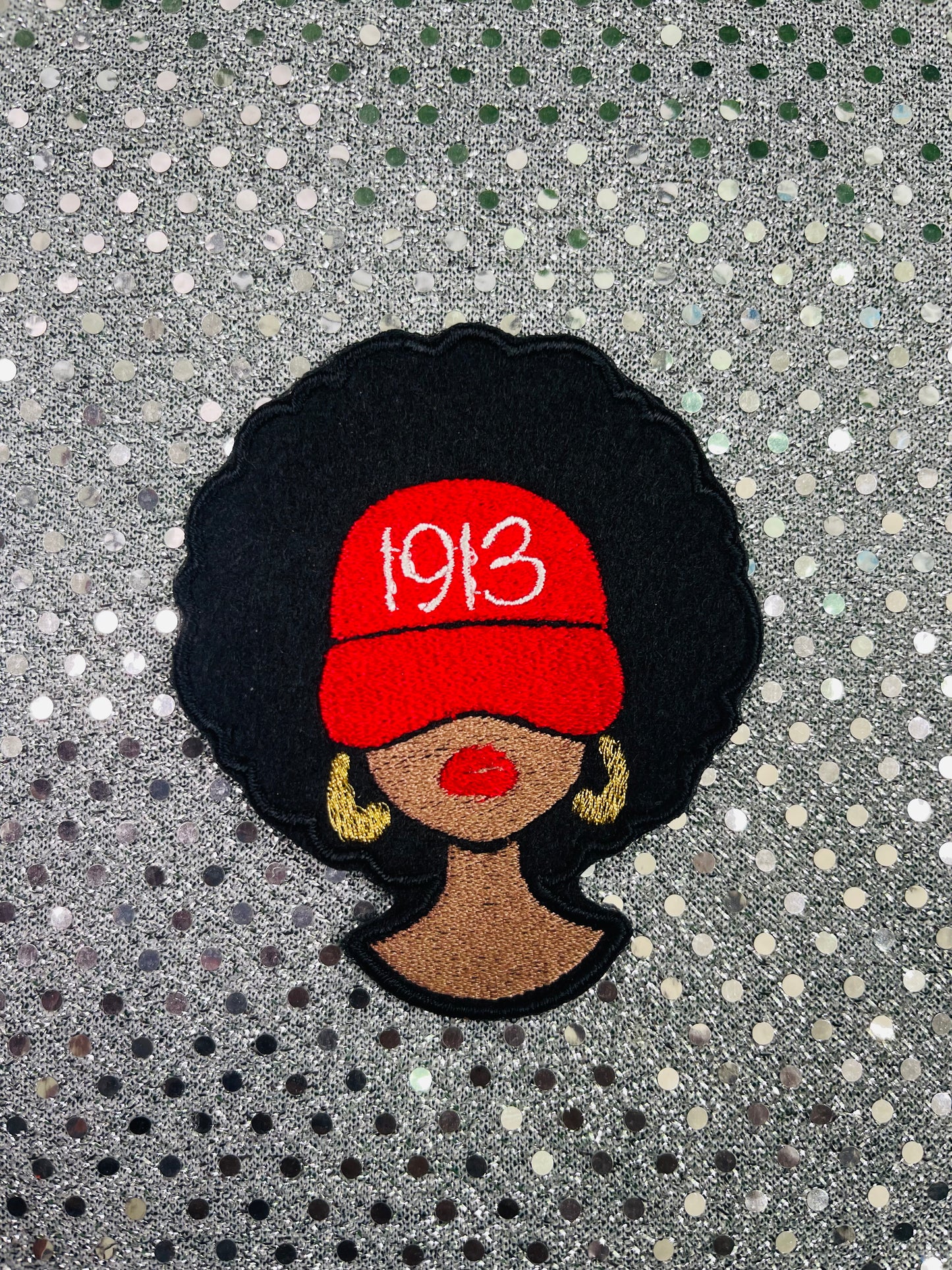 Embroidered patch of a woman wearing a red cap with '1913' on a textured background. Delta Sigma Theta Patch