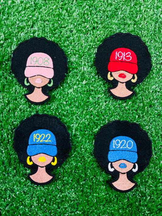Four decorative pins with black hair, colorful hats, and numbers on a green grass-like background.