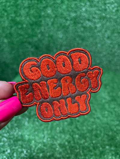 Good Energy patch with bold embroidered letters on a brown background.