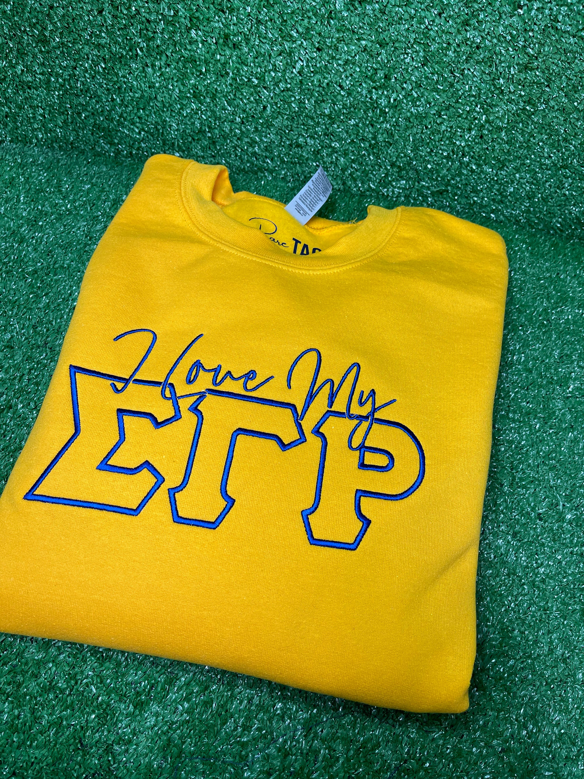 I Love My SGRho Embroidered Sweatshirt - This high-quality sweatshirt features a beautifully embroidered 'I Love My SGRho' design on the front. Made from a soft and durable blend of cotton and polyester, it offers a classic fit with a comfortable crew neck. Perfect for chilly days, casual outings, or chapter meetings, this stylish sweatshirt showcases your Sigma Gamma Rho pride with elegance. 