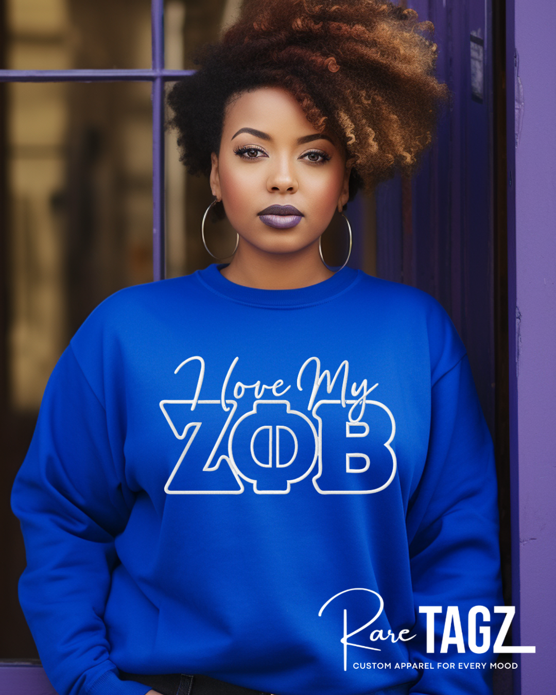 Person wearing a blue sweatshirt with 'I Love My Zeta Phi Beta' text, standing against a purple door. Zeta Phi Beta Sorority Incorporated embroidered sweatshirt