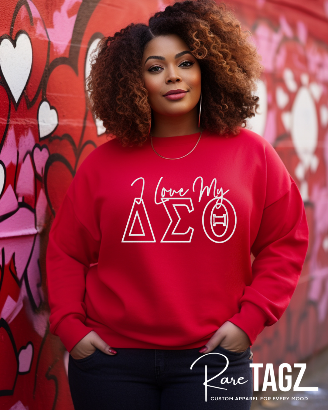 Woman wearing a red sweatshirt with 'I Love My Delta Sigma Theta' design against a colorful heart mural. embroidered sweatshirt 